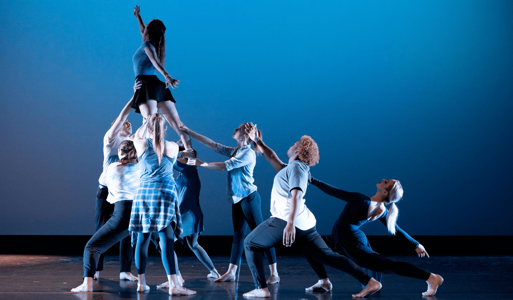 舞者在蓝色背景上把另一个舞者举到空中